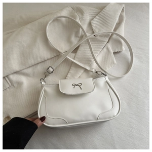 Detail of white PU leather saddle bag with silver bow ornament on corduroy jacket