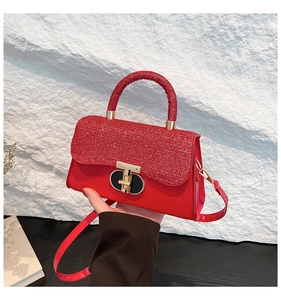 Detail of red glitter handbag featuring a gold T-shaped rotating metal lock and handle