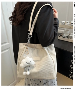 Detail of off-white corduroy tote bag featuring a cute cloud plush charm and textured finish