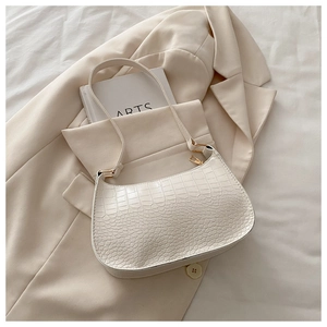Detail of cream hobo bag with crocodile texture and gold metal hardware on blazer