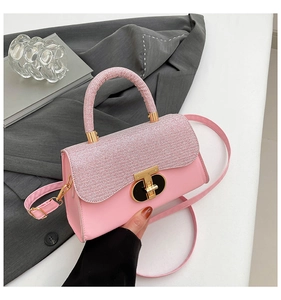 Detail of pink fashion handbag with silver fabric flap and golden T-shaped metal buckle