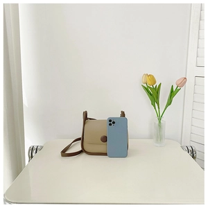Mini khaki and brown crossbody bag showing its compact size next to a smartphone