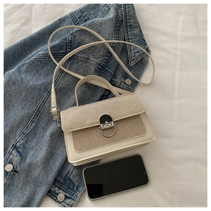 Mini cream leather crossbody bag with glitter panel shown next to a smartphone for scale