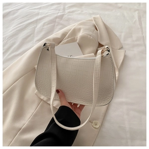 White croc-effect baguette bag with metallic zipper on a beige blazer background