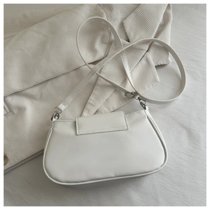Detailed top view of a white PU leather half-moon shoulder bag on a corduroy blazer
