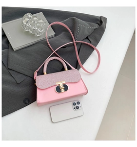 Detail view of pink crossbody bag with glitter flap, metal lock, and smartphone for scale