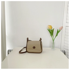 Detail of khaki leather square shoulder bag with brown trim and button closure