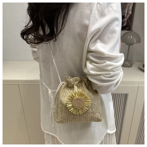 Detail of hand-woven straw bucket bag with sunflower decor and white shoulder strap