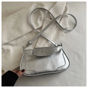 Close-up of a silver metallic crossbody bag featuring a delicate metal bow on the front flap