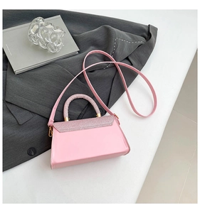 Pink crossbody bag with glitter flap and golden hardware on a stylish business backdrop