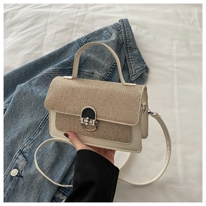 Detail of beige and gold crossbody bag featuring weave texture and silver buckle