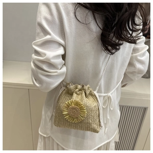 Detail of straw woven bucket bag featuring sunflower decor and drawstring closure
