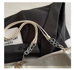 Detail of beige tote bag showing leather and silver metal chain strap on textured fabric
