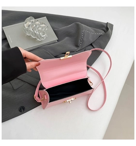 Detail showing the pink glossy leather handbag interior with a metal twist lock closure