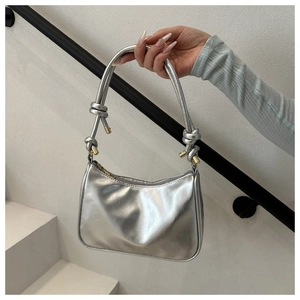 Macro view of silver patent leather hobo bag with distinctive side knot details