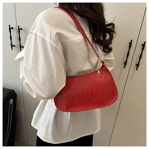 Detail of red crocodile pattern shoulder bag with zipper closure on white shirt model