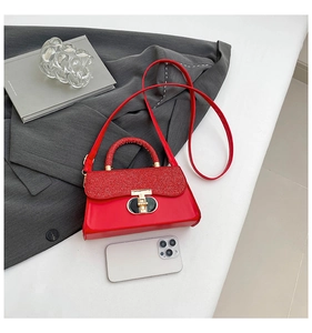 Detail of red sequin and patent leather handbag with gold T-shaped buckle closure