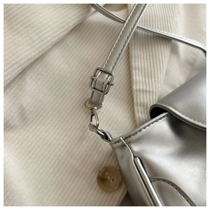Close-up of silver crossbody bag featuring adjustable strap buckle and metallic hardware