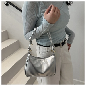 Detail of silver metallic hobo bag with knotted handle and golden metal accents