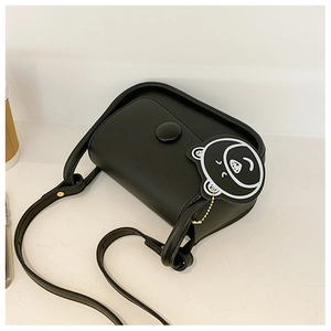 Detail of black minimalist square bag with smooth texture and cute bear charm accent