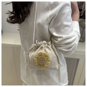 Detail of straw woven bucket bag featuring 3D sunflower decor and drawstring closure
