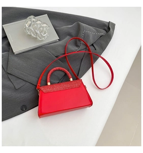 Detailed view of red crossbody bag with shimmering glitter flap and gold metal hardware