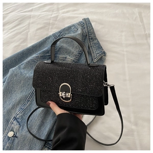 Close-up of black crossbody bag featuring glitter finish flap and silver metal turn-lock