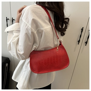 Detail of red crocodile pattern hobo bag worn on shoulder with gold zipper closure