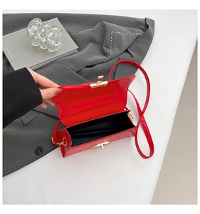 Detail showing the red leather bag interior, golden rotary lock and crossbody strap