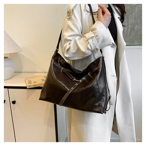 Detail of a large dark brown leather tote bag with adjustable straps on a model