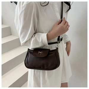 Detail of a dark brown vintage shoulder bag with a silver metal bow buckle accent