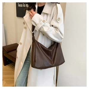 Detail of a large vintage brown tote bag worn over the shoulder with a leather finish