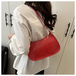 Close-up of red crocodile pattern shoulder bag worn by model in minimalist style