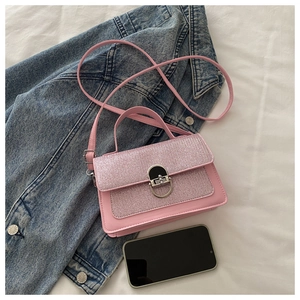 Detail view of a pink glitter crossbody bag with a metal lock and smartphone for size