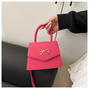 Details der rosaroten Trapez-Handtasche mit goldener Schleifenschließe und Tragegriff