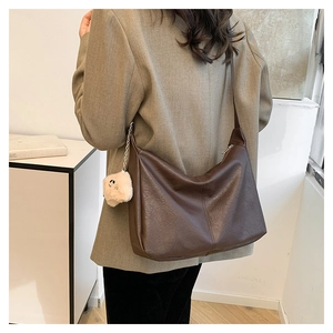 Detail of vintage brown tote bag with pleated texture and cute plush pendant charm