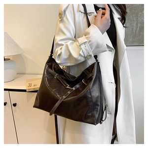 Detail of dark brown oil-wax leather tote bag showing rich texture and belt buckle accent