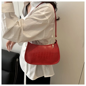 Close-up of red crocodile pattern shoulder bag with golden zipper and vintage crescent shape