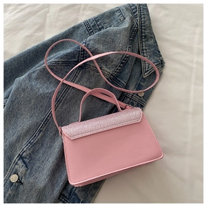 Detailed view of pink mini crossbody bag with glitter trim on flap over denim jacket