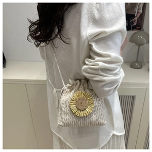 Detail of woven straw bucket bag with a large sunflower ornament and drawstring closure