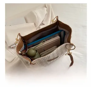 Vista macro dell'ampio interno della borsa tote intrecciata con oggetti quotidiani