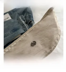 Nahaufnahme der beigen Nylon-Sichel-Tasche mit Logo-Detail und weißen Nähten