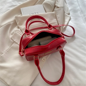 Chic red faux leather bowling bag with dual handles and strap on aesthetic background