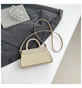 Detail of beige crossbody bag featuring textured woven edges and elegant gold hardware