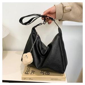 Detail of black large capacity hobo bag in soft leather with a cute plush doll charm