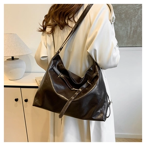Detail of high-shine leather hobo bag with adjustable strap and golden buckle accents