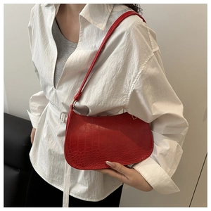 Close-up of red crocodile-embossed half-moon shoulder bag styled with white shirt