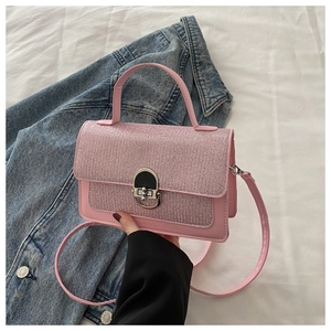 Detailed close-up of pink leather crossbody bag with glitter texture and silver buckle
