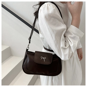 Detail of dark brown leather underarm bag with silver bow accent on stairs background