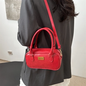 Chic red rectangular bowling bag with gold hardware held by model in casual suit